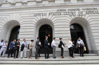 FILE - In this Tuesday, July 9, 2019 file photo, People wait in line to enter the 5th Circuit Court of Appeals to sit in overflow rooms to hear arguments in New Orleans.  President Joe Biden's requirement that all federal employees be vaccinated against COVID-19 is awaiting judgment from a federal appeals court after arguments in New Orleans. An administration attorney told the court Tuesday, March 8, 2022, that a federal judge in Texas overstepped his authority when he blocked the mandate.   (AP Photo/Gerald Herbert, File)