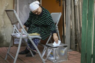 An elderly Moldovan woman casts her vote into a mobile urn, during local elections in Chisinau, Moldova, Nov. 5, 2023. (AP Photo/Aurel Obreja)