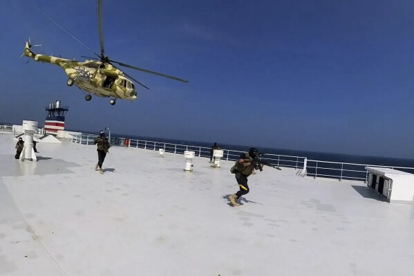 This photo released by the Houthi Media Center shows Houthi forces boarding the cargo ship Galaxy Leader on Sunday, Nov. 19, 2023. Yemen's Houthis have seized the ship in the Red Sea off the coast of Yemen after threatening to seize all vessels owned by Israeli companies. (Houthi Media Center via AP)