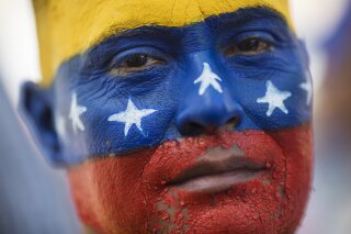 In this Saturday, Nov. 16, 2019 photo, May Vera eyes the camera during a demonstration led by opposition politician Juan Guaido, who's urging masses into the streets to force President Nicolás Maduro from power, in Maracaibo, Venezuela. Vera's face was painted by his niece with the colors of Venezuela's national colors. Guaido called nationwide demonstrations to re-ignite a campaign against Maduro launched in January that has lost steam in recent months. (AP Photo/Rodrigo Abd)