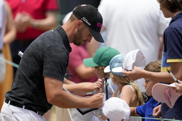 Wyndham Clark signs autographs on the 11th hole during a practice round for the U.S. Open golf tournament Monday, June 10, 2024, in Pinehurst, N.C. (AP Photo/Matt York)