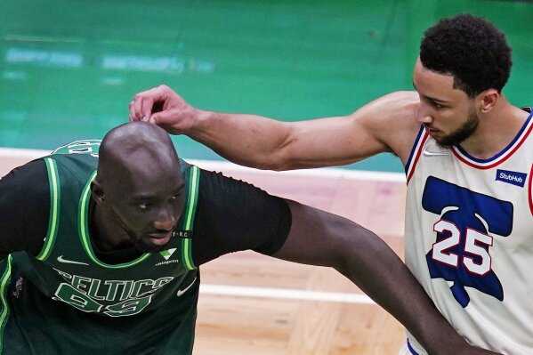 Boston Celtics center Tacko Fall (99) waits for a free throw as Philadelphia 76ers guard Ben Simmons (25) touches his head during the second half of an NBA basketball game, Tuesday, April 6, 2021, in Boston. (AP Photo/Charles Krupa)