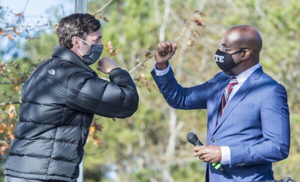 Jon Ossoff, left, and Raphael Warnock exchange elbow bumps during a campaign rally in Augusta, Ga., Monday, Jan. 4, 2021. Democrats Ossoff and Warnock are challenging incumbent Republican Senators David Perdue and Kelly Loeffler in a runoff election on Jan. 5. (Michael Holahan/The Augusta Chronicle via AP)