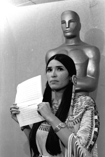 A woman in Native American Indian dress, who indentified herself as Sacheen Littlefeather, tells the audience at the Academy Awards ceremony in Los Angeles March 27, 1973, that Marlon Brando was declining to accept his Oscar as best actor for his role in "The Godfather."  Littlefeather said Brando was protesting "the treatment of the American Indian in motion pictures and on televison, and because of the recent events at Wounded Knee."  (AP Photo)