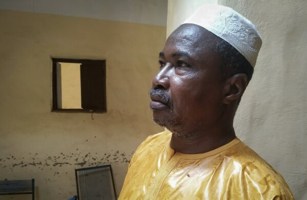 In this photo taken Friday, June 26, 2020, recovering coronavirus patient Harandane Toure, a teacher in his 50s, poses for a photo in his house in Timbuktu, Mali. Toure started taking malaria pills when he first spiked a fever but his illness only worsened. Doctors then told him he is among the hundreds now infected by the coronavirus in this town long fabled for how inaccessible it is from the rest of the world. (AP Photo/Sidi Yahia)