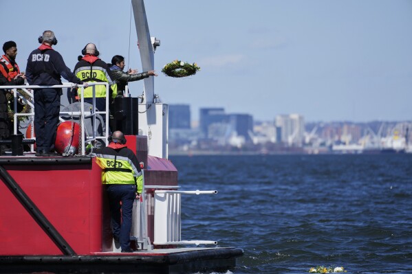 A family member of one of the workers who died during the collapse of the Francis Scott Key Bridge in Baltimore tosses a wreath into the Chesapeake Bay in observance of the one-year anniversary of the disaster, Tuesday, March 25, 2025. (AP Photo/Stephanie Scarbrough)