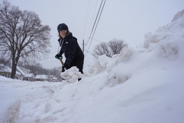 Graphic designer Emily Brewer shovels out her driveway in order to drive to work in Sioux City, Iowa, early on Friday, Jan. 12, 2024. (AP Photo/Carolyn Kaster)