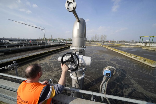 MM employee Marco Bonini touches the water aeration system of a biological purification tank at the MM San Rocco plant, in Milan, Italy, Wednesday, March 20, 2024. Milan purifies its wastewater and a significant portion is then used in agriculture. (AP Photo/Luca Bruno)