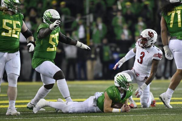 Oregon quarterback Bo Nix (10) lays on the ground after getting past Utah linebacker Mohamoud Diabate (3) as Oregon offensive lineman Marcus Harper II (55) signals a first down during the second half of an NCAA college football game Saturday, Nov. 19, 2022, in Eugene, Ore. (AP Photo/Andy Nelson)