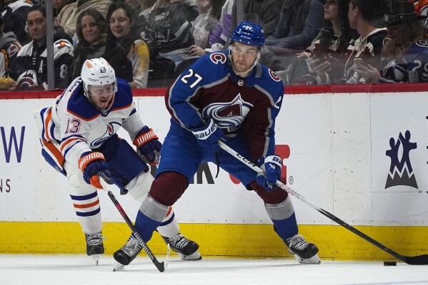Colorado Avalanche left wing Jonathan Drouin, right, looks to pass the puck as Edmonton Oilers center Mattias Janmark defends during the second period of an NHL hockey game Thursday, April 18, 2024, in Denver. (AP Photo/David Zalubowski)