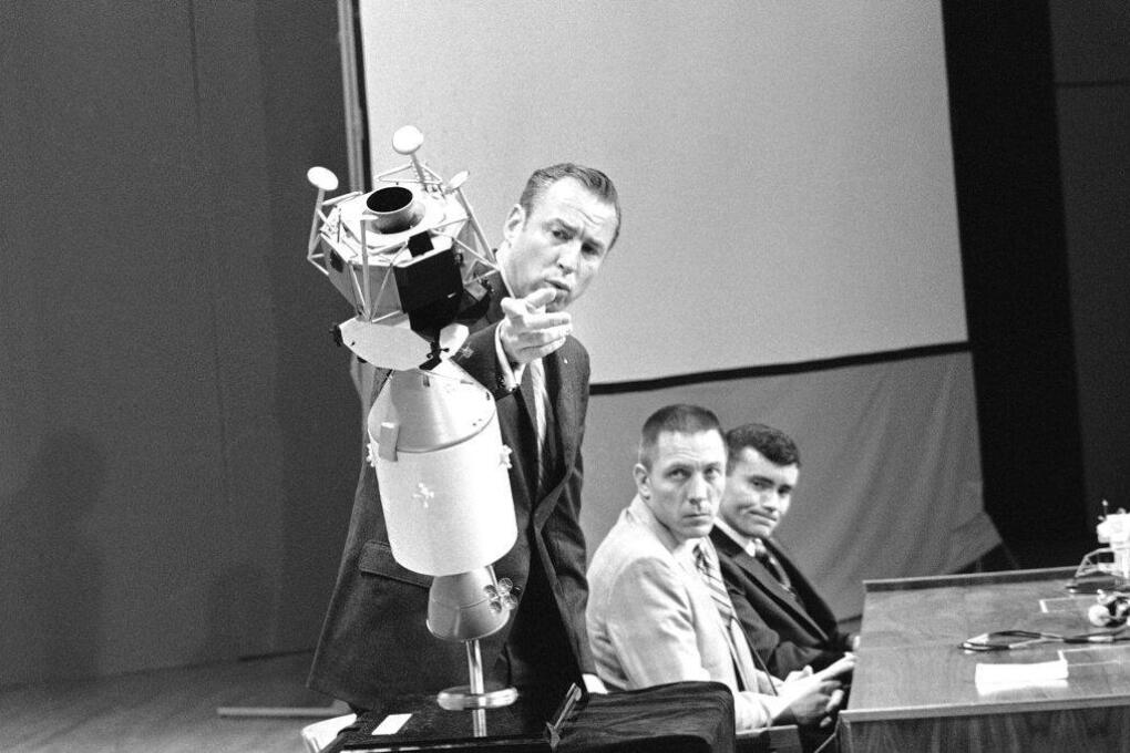 Apollo 13 commander James A. Lovell Jr., uses a scale model to explain how the crew managed to survive the explosion that damaged the service module during the flight to the moon. Tense as they relive the terrifying moments, April 21, 1970 at the televised news conference at Manned Spacecraft Center Houston, Tex., at night are: John L. Swigert Jr., center, command module pilot, and Fred W. Haise Jr., lunar module pilot. (AP Photo)