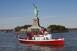 FILE - The fireboat John J. Harvey passes the Statue of Liberty, Oct. 28, 2011, in New York Harbor. A man was arrested Thursday, April 11, 2024, for allegedly taking the decommissioned New York City fire boat for an overnight cruise on the Hudson River, before becoming stuck and jumping ship. He then boarded a second stolen vessel, police said, which he sailed roughly one nautical mile (1.8 kilometers) south until he was taken into custody on its deck. (AP Photo/Mark Lennihan, File)