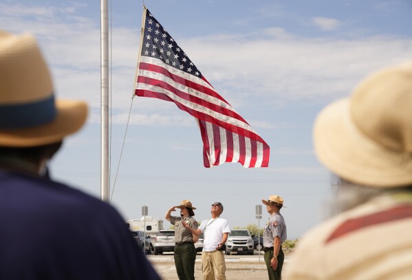 Greg Kogita, center, prepares to receive a World War II-era flag signed by survivors of Minidoka and other camps during a flag ceremony for a group of Minidoka Pilgrimage attendees at Minidoka National Historic Site, Saturday, July 8, 2023, in Jerome, Idaho. (AP Photo/Lindsey Wasson)