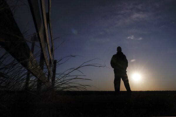 Lateef Dowdell watches the sunrise from what remains of land once belonging to his uncle Gil Alexander, who was the last active Black farmer in the community of Nicodemus, Kan., Thursday, Jan. 14, 2021. Dowdell moved back to Nicodemus, a settlement founded by former slaves known as "exodusters" in the 1870s, several years earlier to take over the farm after his uncle died, but soon after lost most of the land when the bank foreclosed. New legislation in Congress aims to remedy historical inequities in government farm programs that have helped reduce the number of Black farmers in the United States from about a million in 1920 to less than 50,000 today. (AP Photo/Charlie Riedel)