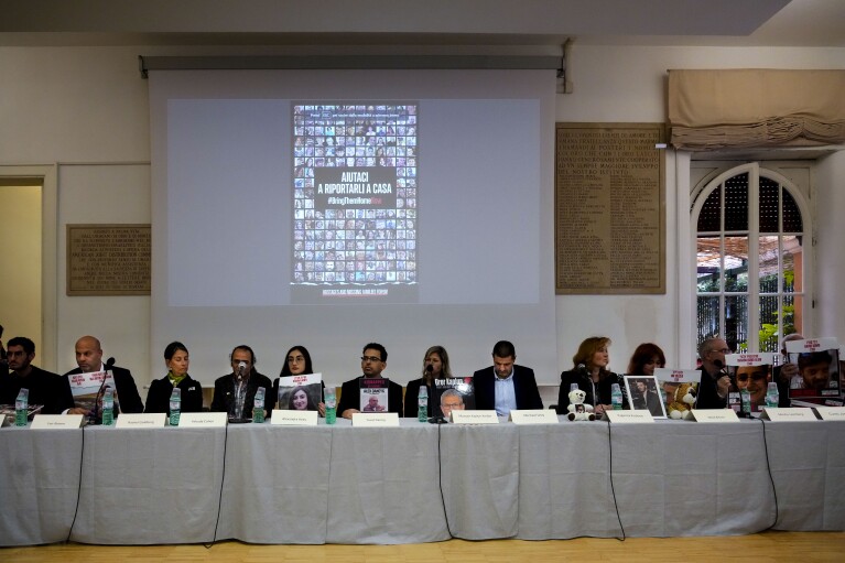 Family members attend a press conference at the Italian Jewish Center in Rome, Wednesday, Nov. 22, 2023, with other representatives of the families of the Israelis abducted by Hamas on Oct. 7 and believed to be held hostages in Gaza, shortly after they met with Pope Francis at The Vatican. The slide on the screen reads in Italian: "Help us bring them home". (AP Photo/Gregorio Borgia)