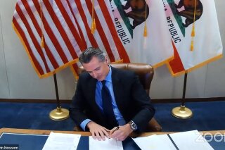 This image made from video from the Office of the Governor shows California Gov. Gavin Newsom signing into law a bill that establishes a task force to come up with recommendations on how to give reparations to Black Americans on Wednesday, Sept. 30, 2020, in Sacramento, Calif. The law establishes a nine-member task force to come up with a plan for how the state could give reparations to Black Americans, what form those reparations might take and who would be eligible to receive them. (Office of the Governor via AP)