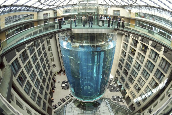 FILE - People gather on the top of the AquaDom aquarium at the Sea Life tourist attraction in Berlin, on July 27, 2015. Prosecutors in Berlin say they have closed their investigation into the spectacular collapse of a huge aquarium last December after an expert report failed to pin down a reason why the tank burst. The AquaDom aquarium, which stood in a hotel lobby, burst in the early hours of Dec. 16, sending 1 million liters (264,000 gallons) of water gushing into the building and the street outside. (Joerg Carstensen via DPA, File)