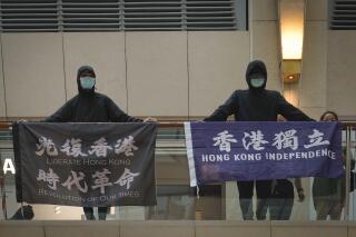 FILE - In this June 9, 2020, file photo, protesters show a banner "Librate Hong Kong, Revolution of out time," left, and "Hong Kong Independence" in a shopping mall during a protest in Hong Kong. Hong Kong police have arrested a 40-year-old man on suspicion of using seditious words after a flag with a banned protest slogan was seen hanging outside his apartment, Monday, June 22, 2021. (AP Photo/Vincent Yu, File)