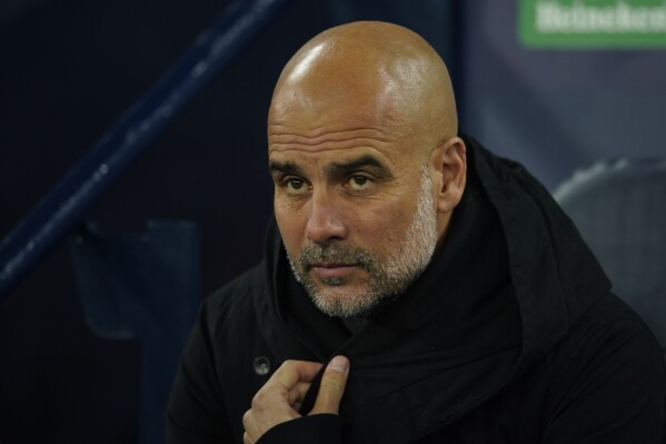 Manchester City's head coach Pep Guardiola sits on the bench before the group G Champions League soccer match between Manchester City and RB Leipzig at the Etihad stadium in Manchester, England, Tuesday, Nov. 28, 2023. (AP Photo/Dave Thompson)