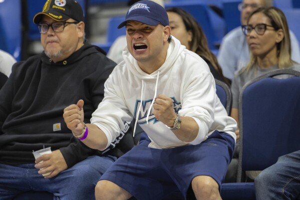 Reggaeton singer Jowell cheers during a basketball game between the Guaynabo Mets and the Bayamón Vaqueros, at the Ruben Rodríguez Coliseum in Bayamón, Puerto Rico, Monday, July 1, 2024. Puerto Rico’s professional basketball league is experiencing a renaissance thanks to reggaeton stars like Bad Bunny, Ozuna and Anuel AA, who are stepping into the financial game, buying local teams and helping to stack up a loyal fan base. (AP Photo/Alejandro Granadillo)
