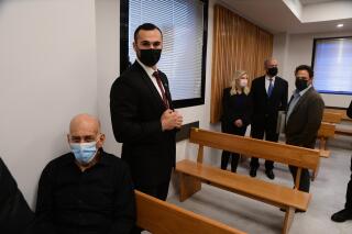 El ex primer ministro israelí Ehud Olmert, izquierda, permanece sentado al tiempo que su homólogo Benjamin Netanyahu, segundo de derecha a izquierda, llega con su esposa Sarah a la corte en Tel Aviv el lunes 10 de enero de 2022, para una audiencia preliminar en una demanda por difamación. (Avshalom Sassoni/Pool Photo vía AP)