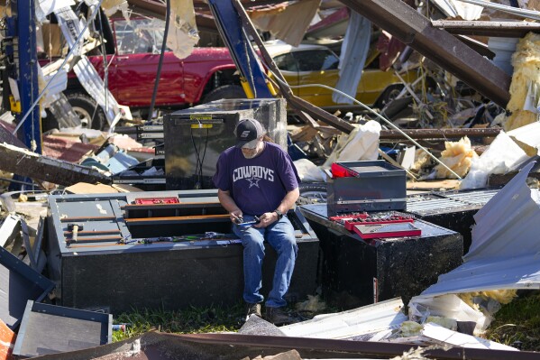 An employee of a body shop collects tools from near damage the morning after a tornado rolled through, Sunday, May 26, 2024, in Valley View, Texas. Powerful storms left a wide trail of destruction Sunday across Texas, Oklahoma and Arkansas after obliterating homes and destroying a truck stop where drivers took shelter during the latest deadly weather to strike the central U.S. (AP Photo/Julio Cortez)