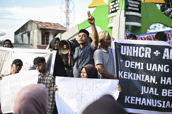 Protesters hold posters during a rally in Sabang, Aceh province, Indonesia, Monday, Dec. 18, 2023. More than 200 people have protested against the continued arrival of Rohingya refugees by boat on an island in Indonesia. Over 1,500 Rohingya who fled violent attacks in Myanmar and are leaving camps in Bangladesh have arrived in Aceh off the tip of Sumatra since November. Posters reads "Kick out UNHCR and IOM", and "UNHCR and its agents, do you really have to trade humanity for money?" (AP Photo/Reza Saifullah)