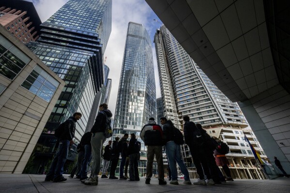 People stand in front of the city's largest construction site with four new high-rise buildings in Frankfurt, Germany, Sept. 24, 2024. (AP Photo/Michael Probst, file)