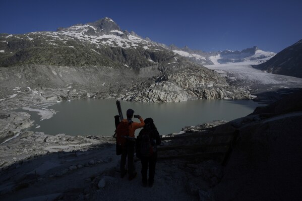Matthias Huss, of the Federal Institute of Technology in Zurich and glacier monitoring group GLAMOS, and Monica Ursina Jaeger arrive at the Rhone Glacier near Goms, Switzerland, June 10, 2025. (AP Photo/Matthias Schrader)