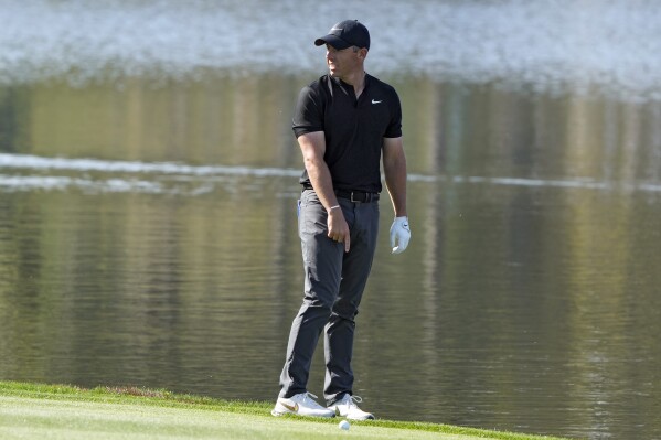 Rory McIlroy, of Northern Ireland, points to near where his shot went into the water on the 18th hole during the first round of The Players Championship golf tournament Thursday, March 14, 2024, in Ponte Vedra Beach, Fla. (AP Photo/Lynne Sladky)