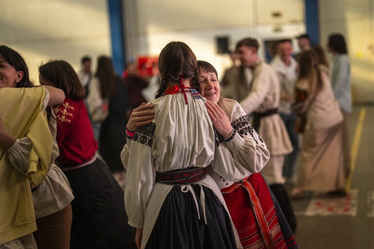 Women wearing traditional Ukrainian costumes greet and dance with others in a market in Kyiv, Ukraine, Sunday, April 28, 2024. (AP Photo/Francisco Seco)
