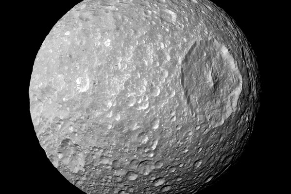 This Feb. 13, 2010 image provided by NASA shows Saturn's moon Mimas and it's large Herschel Crater, captured by the Cassini spacecraft. The crater is 130 kilometers (80 miles) wide. Astronomers have reported the best evidence yet of a vast, relatively new ocean beneath the icy exterior of Mimas, believed between 5 million and 15 million years old. The findings were published Wednesday, Feb. 7, 2024, in the journal Nature. (NASA/JPL-Caltech/Space Science Institute via AP)