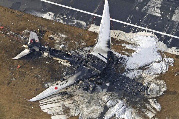 FILE - This aerial photo show the burn-out Japan Airlines plane at Haneda airport in Tokyo, on Jan. 3, 2024. The 379 passengers of Japan Airlines Flight JAL-516 didn't expect their plane to burst into flames just as it was about to touchdown at Tokyo’s Haneda airport Tuesday evening. A smaller coast guard Bombardier Dash-8 aircraft, preparing to take off to deliver urgent aid to quake-hit central Japan, was using the same runway when the two collided. The Associated Press collected accounts from witnesses, officials and transcripts of the traffic controls communication. (Kyodo News via AP, File)
