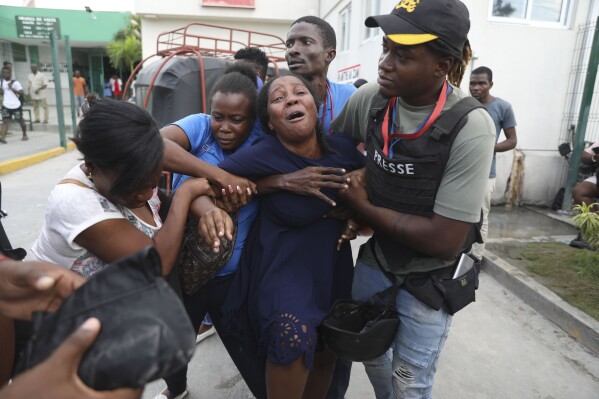 The wife of a journalist, who was shot during an armed gang attack on the General Hospital, cries as an ambulance arrives with his body, at a different hospital in Port-au-Prince, Haiti, Tuesday, Dec. 24, 2024. (AP Photo/Odelyn Joseph)