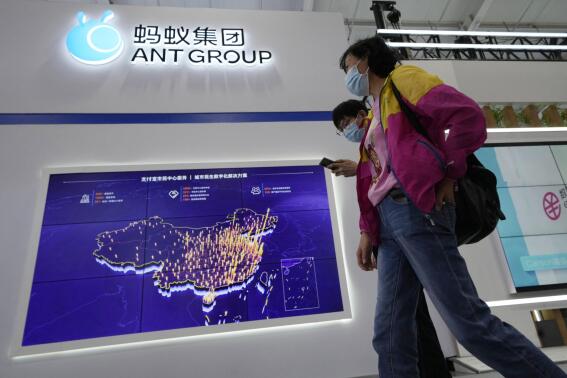 FILE - Visitors past by the booth for Ant Group at the China International Fair for Trade in Services (CIFTIS) in Beijing, China on Monday, Sept. 6, 2021. Chinese regulators have said e-commerce giant Alibaba’s finance affiliate Ant Group can raise $1.5 billion for its consumer finance unit in an important step forward after the government called off a planned IPO two years ago and ordered the firm to restructure. (AP Photo/Ng Han Guan, File)