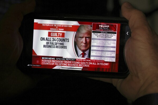 A member of the media looks at news of former President Donald Trump on his phone after the conclusion of Trump's hush money trial, in New York, Thursday, May 30, 2024. (Michael M. Santiago/Pool Photo via AP)
