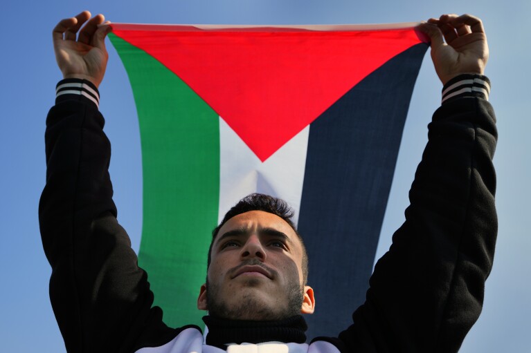 A demonstrator during a protest to demand a ceasefire in the Gaza Strip and support Palestinians, near the headquarters of the United Nations Economic and Social Commission for Western Asia (ESCWA) in Beirut, Lebanon, on Sunday, February 11, 2024. Raised the Palestinian flag.  (AP Photo/Bilal Hussain)