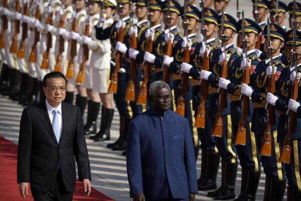 FILE - Chinese Premier Li Keqiang, left, and Solomon Islands Prime Minister Manasseh Sogavare review an honor guard during a welcome ceremony at the Great Hall of the People in Beijing, on Oct. 9, 2019.  China’s Foreign Minister Wang will visit Solomon Islands this week in what the South Pacific nation’s leader said was a “milestone” in his country’s relationship with China, amid concerns over their security pact that could allow Chinese military personnel on the islands. (AP Photo/Mark Schiefelbein, File)