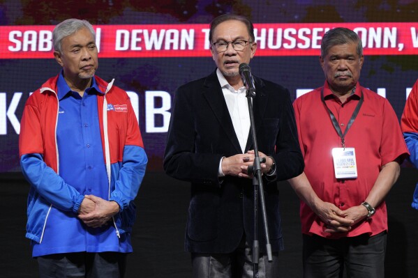 Malaysian Prime Minister Anwar Ibrahim, centre, speaks to media as deputy prime minister Ahmad Zahid Hamidi, left, standing with other leaders after announcing the result of state election at UMNO headquarters in Kuala Lumpur, Malaysia Saturday, Aug. 12, 2023. Malaysian state elections have ended in a return to the status quo, with Prime Minister Anwar Ibrahim's government and the Islamist opposition each retaining control of three states as expected. (AP Photo/Vincent Thian)
