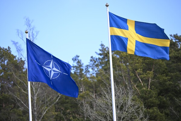 The NATO flag, left, is raised next to the Swedish flag during a ceremony at the Musko navy base Stockholm, Monday, March 11, 2024. Sweden’s national flag has been raised at NATO headquarters in Brussels, cementing the Nordic country’s place as the 32nd member of the alliance two years after Russia’s invasion of Ukraine persuaded its reluctant public to seek safety under NATO’s security umbrella. (Fredrik Sandberg/TT News Agency via AP)