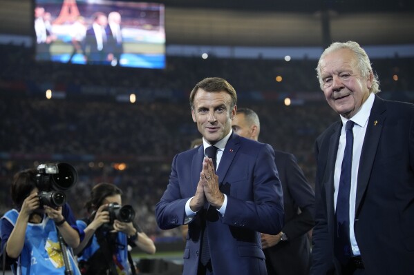 French President Emmanuel Macron gestures as he stands alongside Bill Beaumont, the chairperson of World Rugby, during the opening ceremony before the Rugby World Cup Pool A match between France and New Zealand at the Stade de France in Saint-Denis, north of Paris, Friday, Sept. 8, 2023. (AP Photo/Christophe Ena)