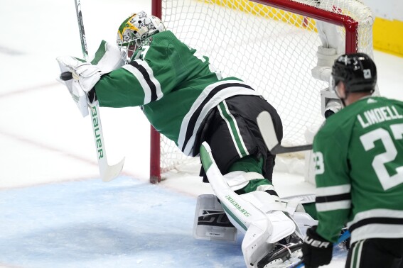 Dallas Stars goaltender Jake Oettinger makes a diving save during a St. Louis Blues power play as the Stars' Esa Lindell looks on in the first period of an NHL hockey game in Dallas, Wednesday, April 17, 2024. (AP Photo/Tony Gutierrez)