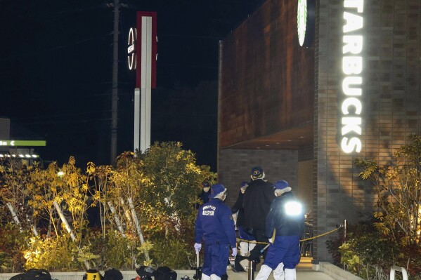 Investigators work at the site of a shooting in Shikokuchuo City, Ehime prefecture, western Japan Sunday, Jan. 14, 2024. Japanese police were searching Monday for a suspect who fatally shot a customer at a Starbucks in what was reportedly a gang-related crime. (Kyodo News via AP)