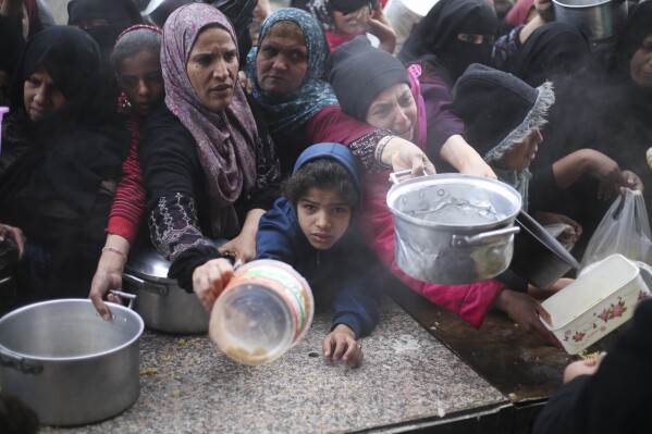 Palestinos fazem fila para distribuir alimentos gratuitos durante a ofensiva aérea e terrestre israelense em Khan Yunis, Faixa de Gaza, sexta-feira, 2 de fevereiro de 2024. (AP Photo/Hatem Ali)