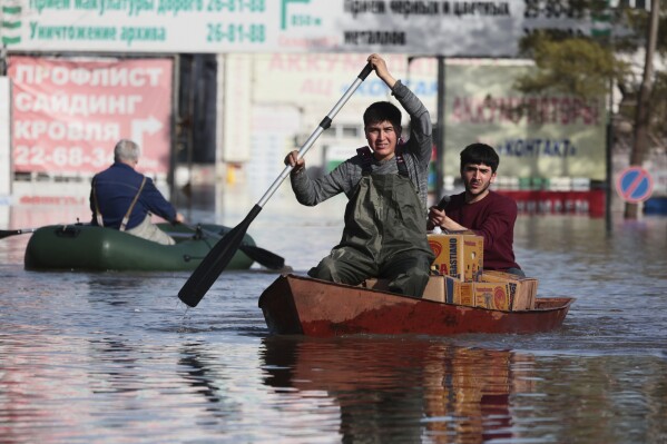 Two men ride a boat as they deliver food in a flooded area in Orenburg, Russia, on Thursday, April 11, 2024. Russian officials are scrambling to help homeowners displaced by floods, as water levels have risen in the Ural River. The river's water level in the city of Orenburg was above 10 meters (33 feet) Wednesday, state news agency Ria Novosti reported, citing the regional governor. (AP Photo)