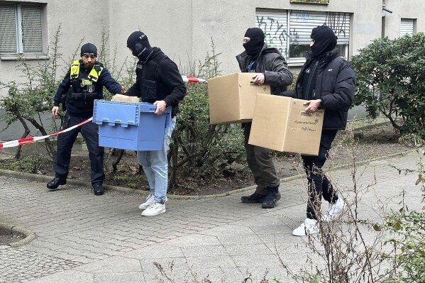 Investigators enter the home of former RAF terrorist Daniela Klette with boxes and cartons, in Berlin, Wednesday, Feb. 28, 2024. A hand grenade and other dangerous objects were found in searches of the Berlin apartment where a suspected former member of the left-wing militant Red Army Faction group was arrested this week after more than three decades in hiding, police said Thursday. Daniela Klette, 65, was arrested on Monday afternoon. (Paul Zinken/dpa via AP)
