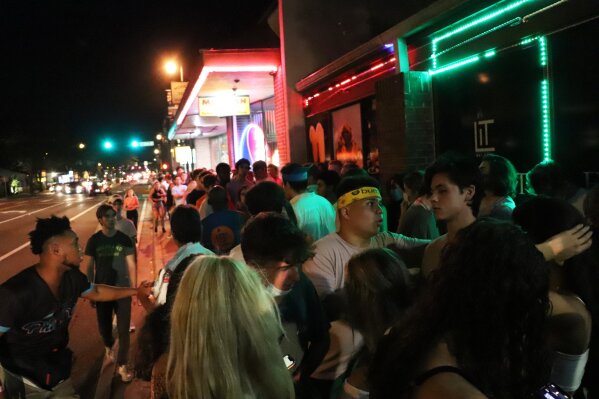 In this photo provided by Fresh Take Florida, people wait in line outside a bar following a University of Florida football game, Saturday, Sept. 16, 2020, in Gainesville, Fla. College students across Florida are packing bars off campus and private parties while breaking rules about wearing masks and maintaining social distance during the fall semester – and other students themselves are often reporting violations to authorities. (Lauren Witte/Fresh Take Florida via AP)