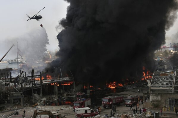 An army helicopter drops water on a fire at warehouses at the seaport in Beirut, Lebanon, Thursday, Sept. 10. 2020. A huge fire broke out Thursday at the Port of Beirut, triggering panic among residents traumatized by last month's massive explosion that killed and injured thousands of people. (AP Photo/Hassan Ammar)
