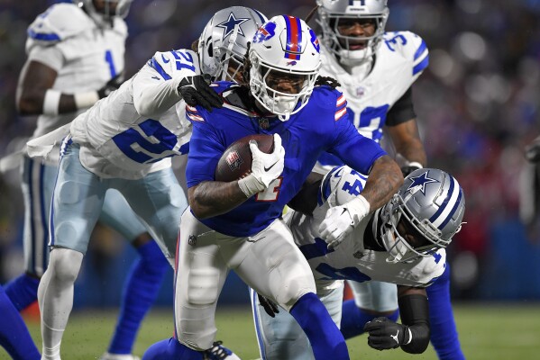 Buffalo Bills running back James Cook (4) tries to avoid the grasp of Dallas Cowboys cornerback Stephon Gilmore (21) during the second quarter of an NFL football game, Sunday, Dec. 17, 2023, in Orchard Park, N.Y. (AP Photo/Adrian Kraus)