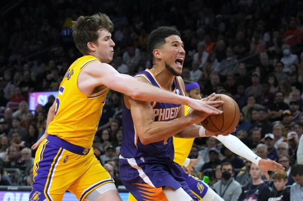 Los Angeles Lakers guard Austin Reaves, left, fouls Phoenix Suns guard Devin Booker during the second half of an NBA basketball game Tuesday, April 5, 2022, in Phoenix. The Suns won 121-110. (AP Photo/Rick Scuteri)